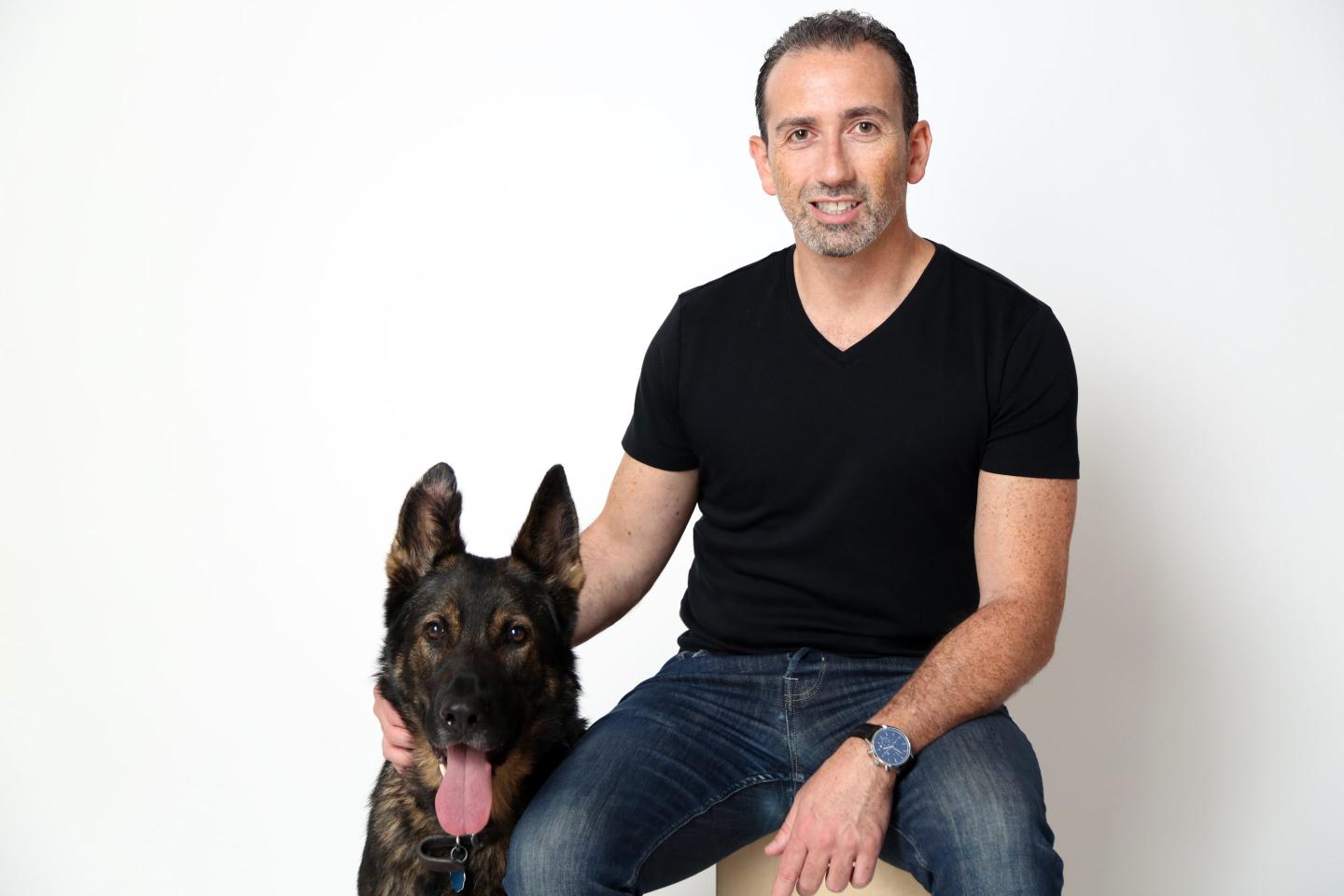 Jonathan Bensamoun (right) sits on a stool next to his German Shepherd