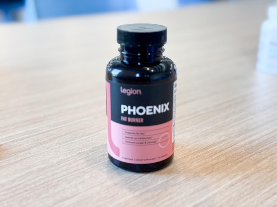 A bottle of Legion Phoenix Fat Burner sits on a wooden countertop.