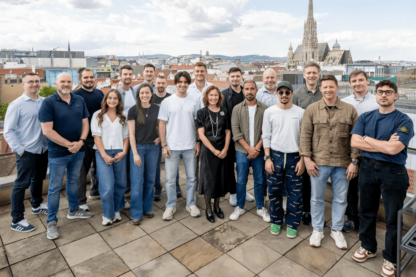 19 of Cyclops' members stand smiling at the camera from their offices in Vienna, Austria.