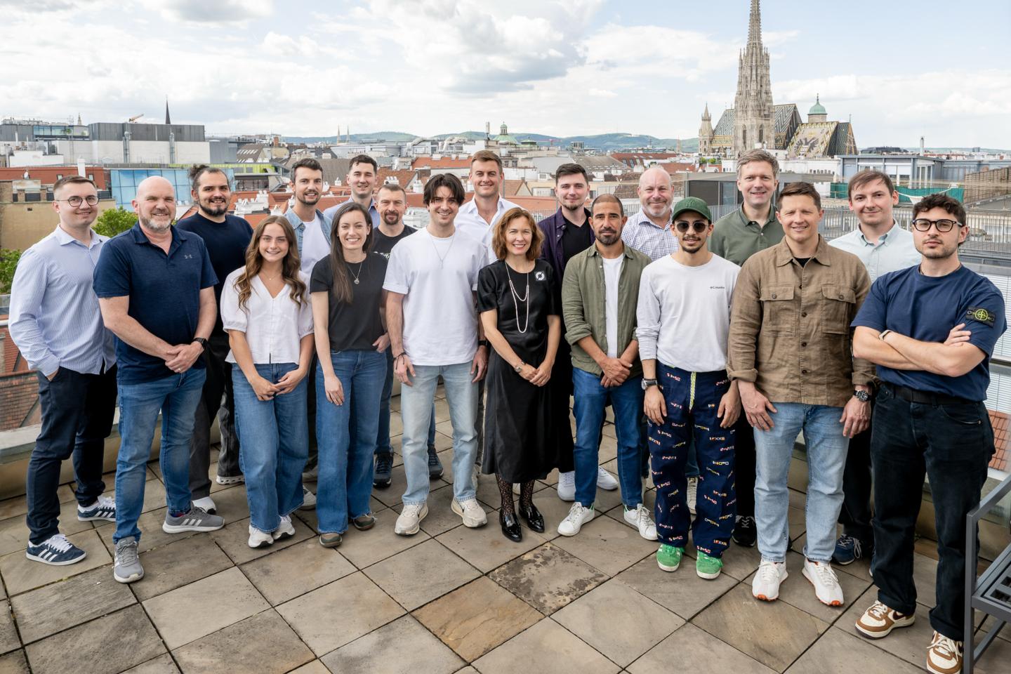 19 of Cyclops' members stand smiling at the camera from their offices in Vienna, Austria.