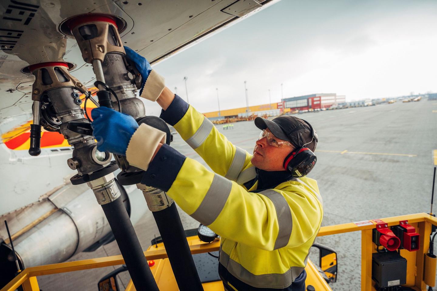 DHL plane being refuelled at airport by man in high-vis jacket