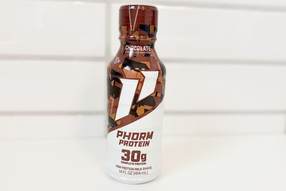 A bottle of chocolate-flavored 1st Phorm Protein sitting on a white countertop.