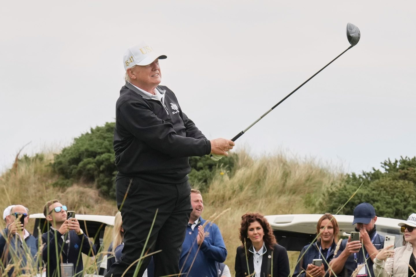 President Donald Trump tees off during the opening ceremony for the Trump International Golf Links golf course.