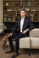 Yevgeny Dibrov wears a suit and sits on a couch