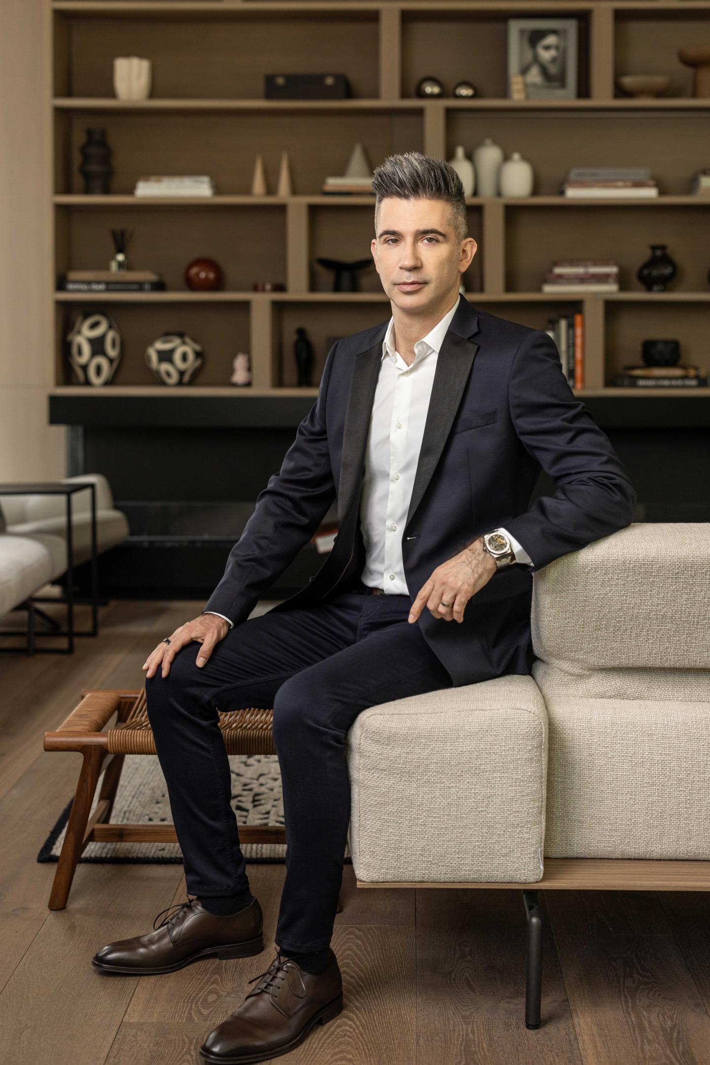 Yevgeny Dibrov wears a suit and sits on a couch
