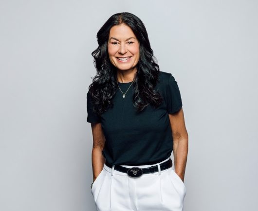 Andrea brimmer, smiling as she stands with her hands I her pant pockets