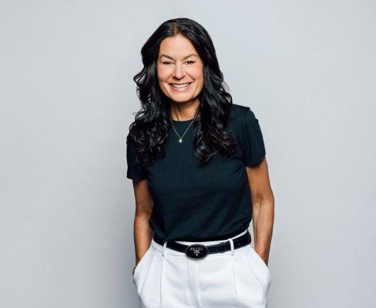 Andrea brimmer, smiling as she stands with her hands I her pant pockets