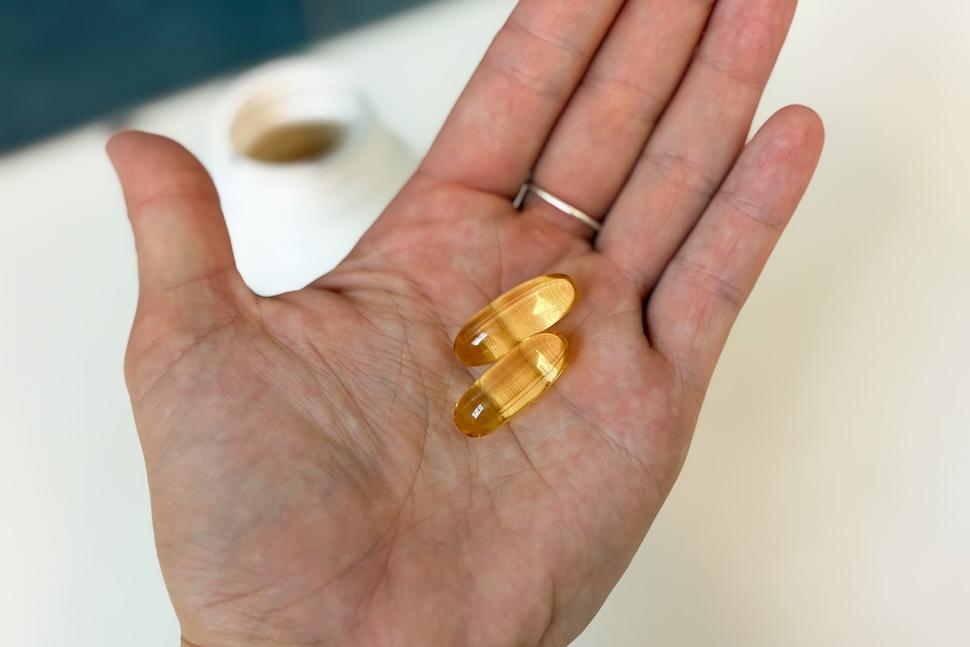 Closeup shot of an open palm holding two AG Omega3 capsules