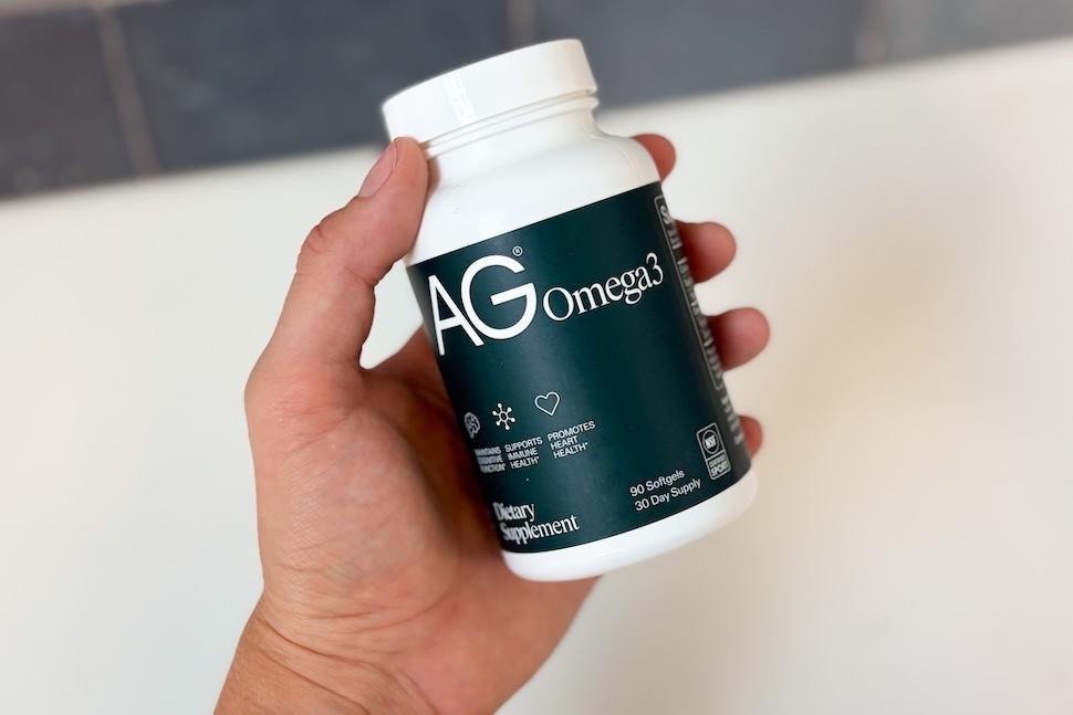 Closeup shot of a hand holding a bottle of AG Omega3
