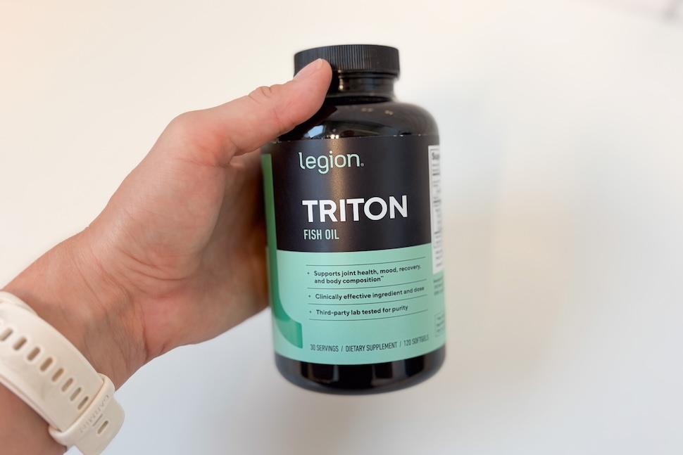 Closeup of a hand holding a bottle of Legion Triton