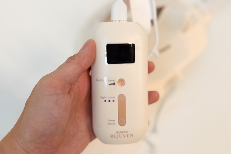 Closeup of a hand holding the control for the RENPHO Rejuven Red Light Therapy Mask