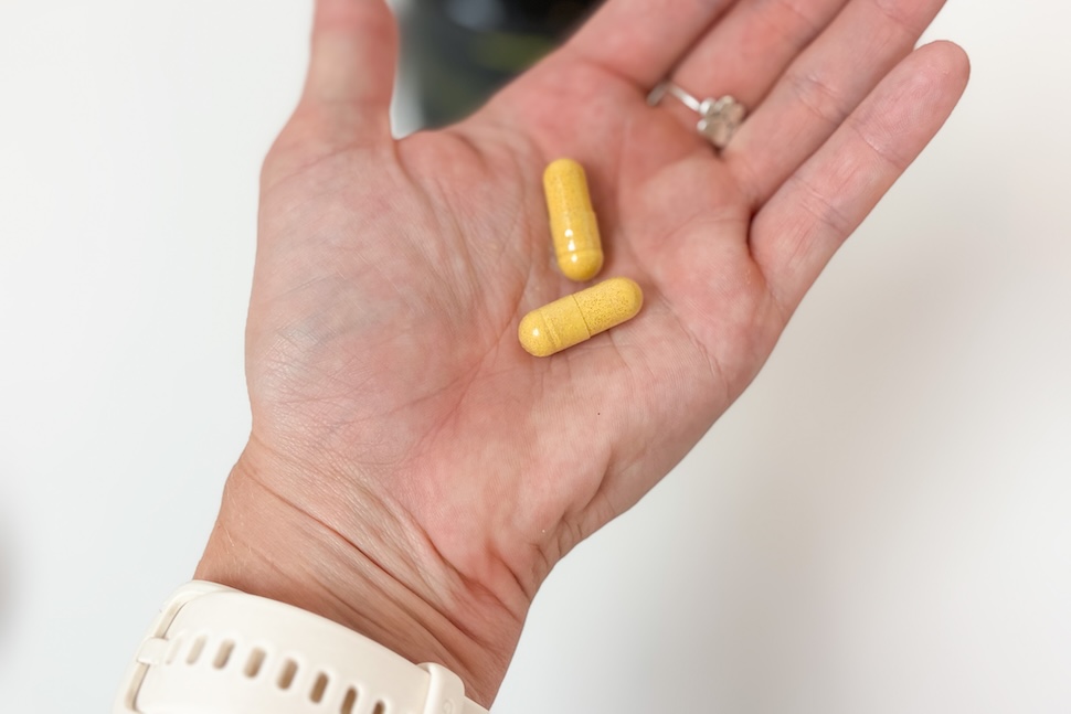 Closeup of a palm holding two yellowish Swolverine Incivra capsules