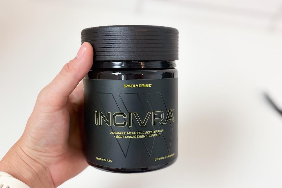 A hand golding a black canister of Swolverine Incivra