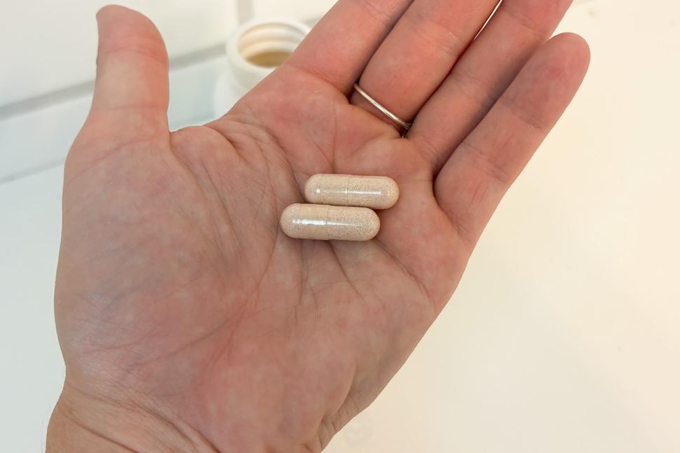Closeup of an open palm holding two Wellah Probiotic capsules