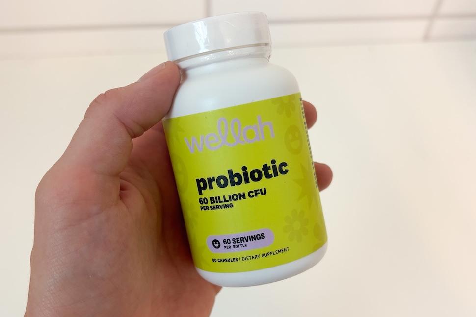 Closeup of a hand holding a Wellah Probiotic bottle