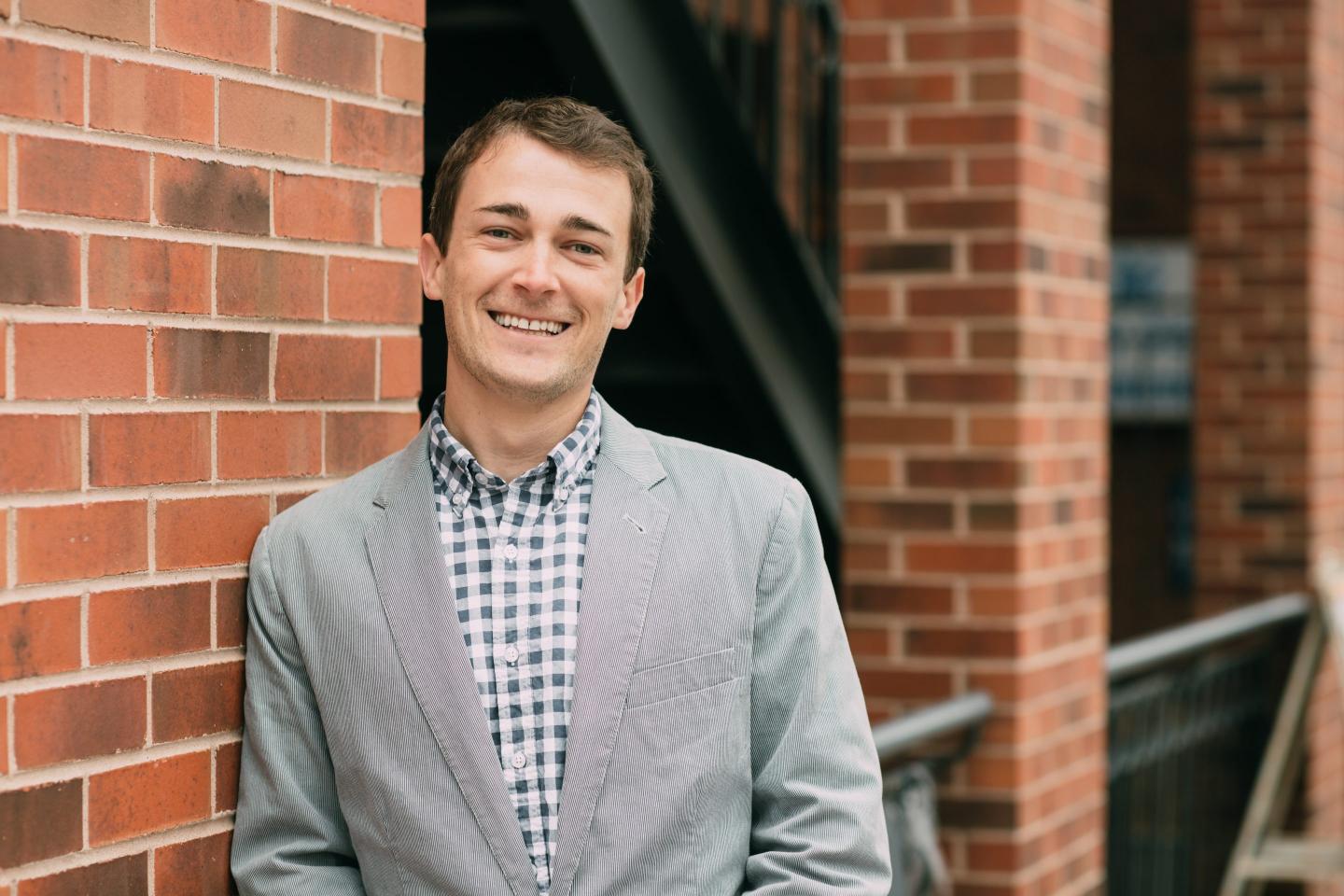 Leadership content creator George Stern poses in front of a brick wall
