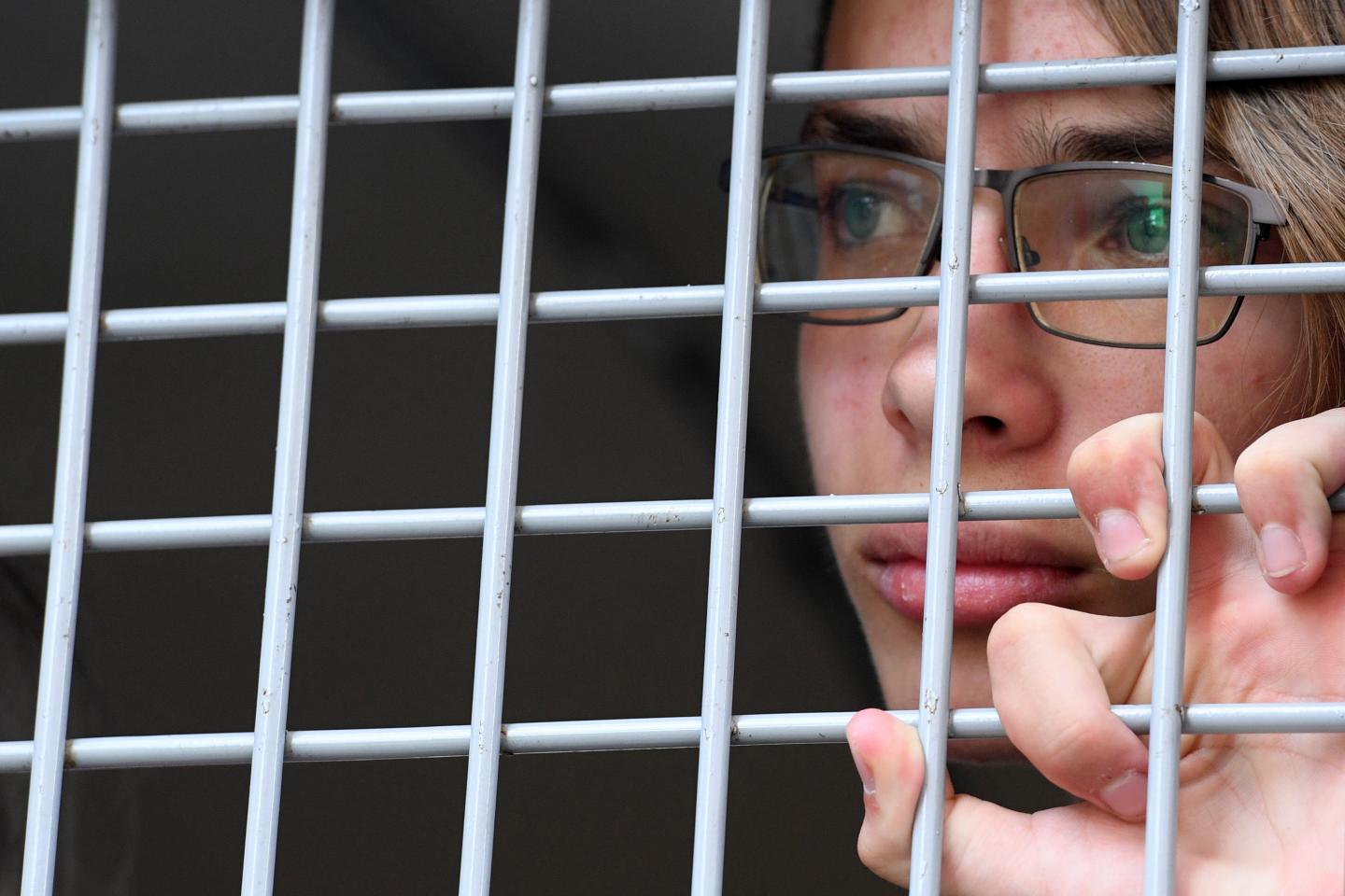 A person looking through a metal grid on a window