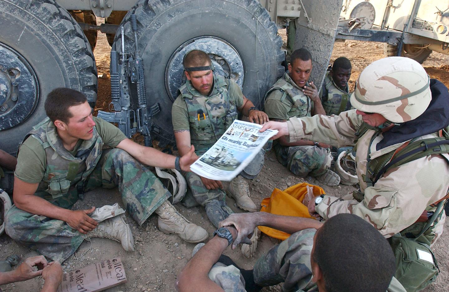 In this image released by the US Navy 07 April, 2003, Command Sgt Maj John Sparks, delivers copies of Stars and Stripes 04 April to US Marines from Weapons Platoon, 3-2 India Company.
