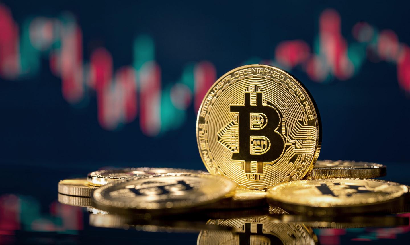 A picture of Bitcoin with a backdrop of a trading chart.