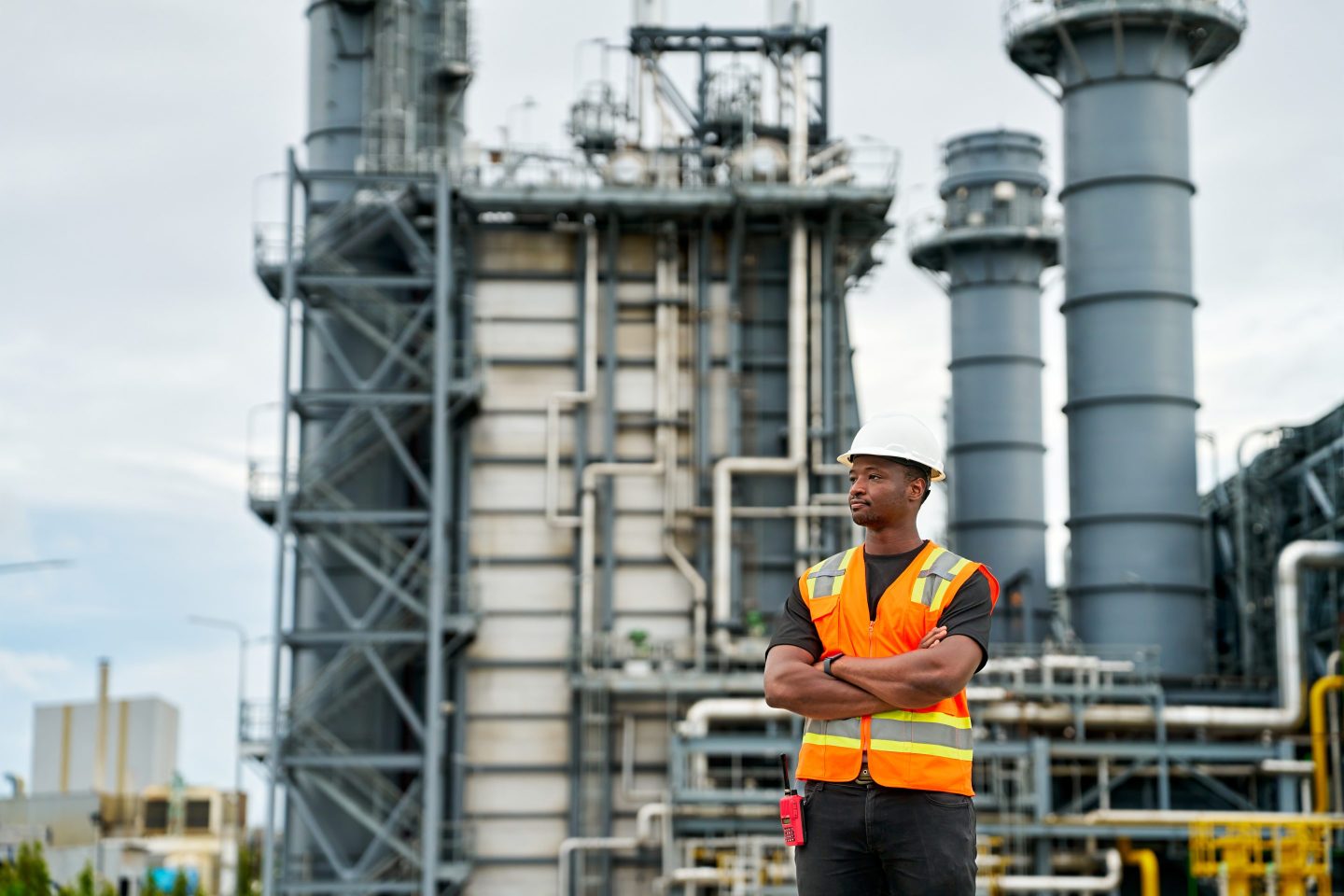 Young energy worker stands in front of power plant
