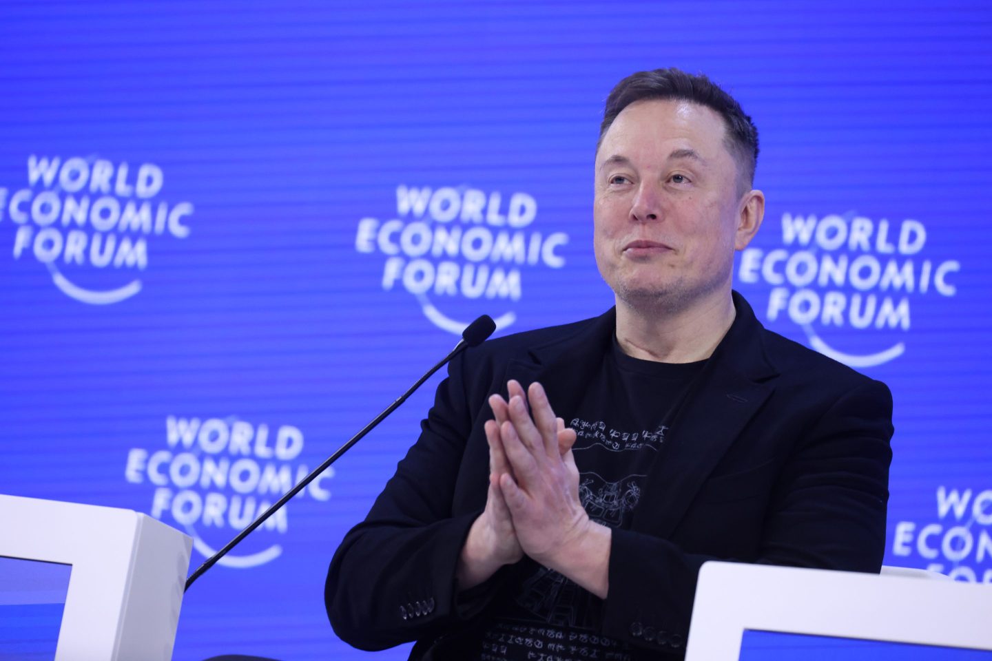 Man in black in front of a blue background.