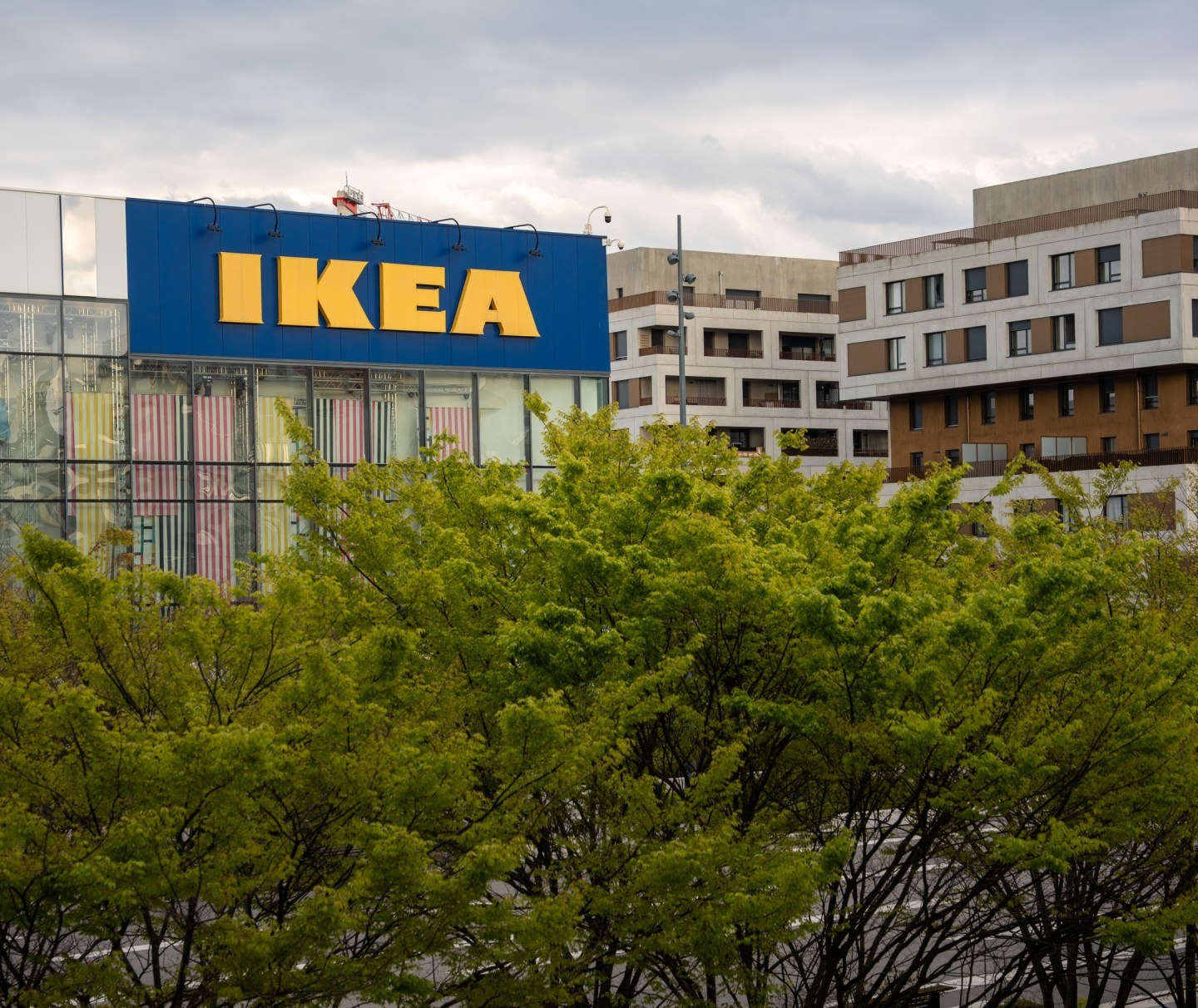 A view of an IKEA store building surrounded by urban vegetation near Lyon France, 2026.