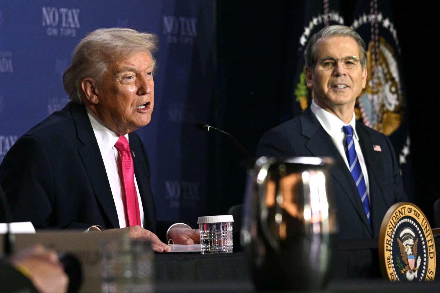 Donald Trump and Scott Bessent sit next to each other.