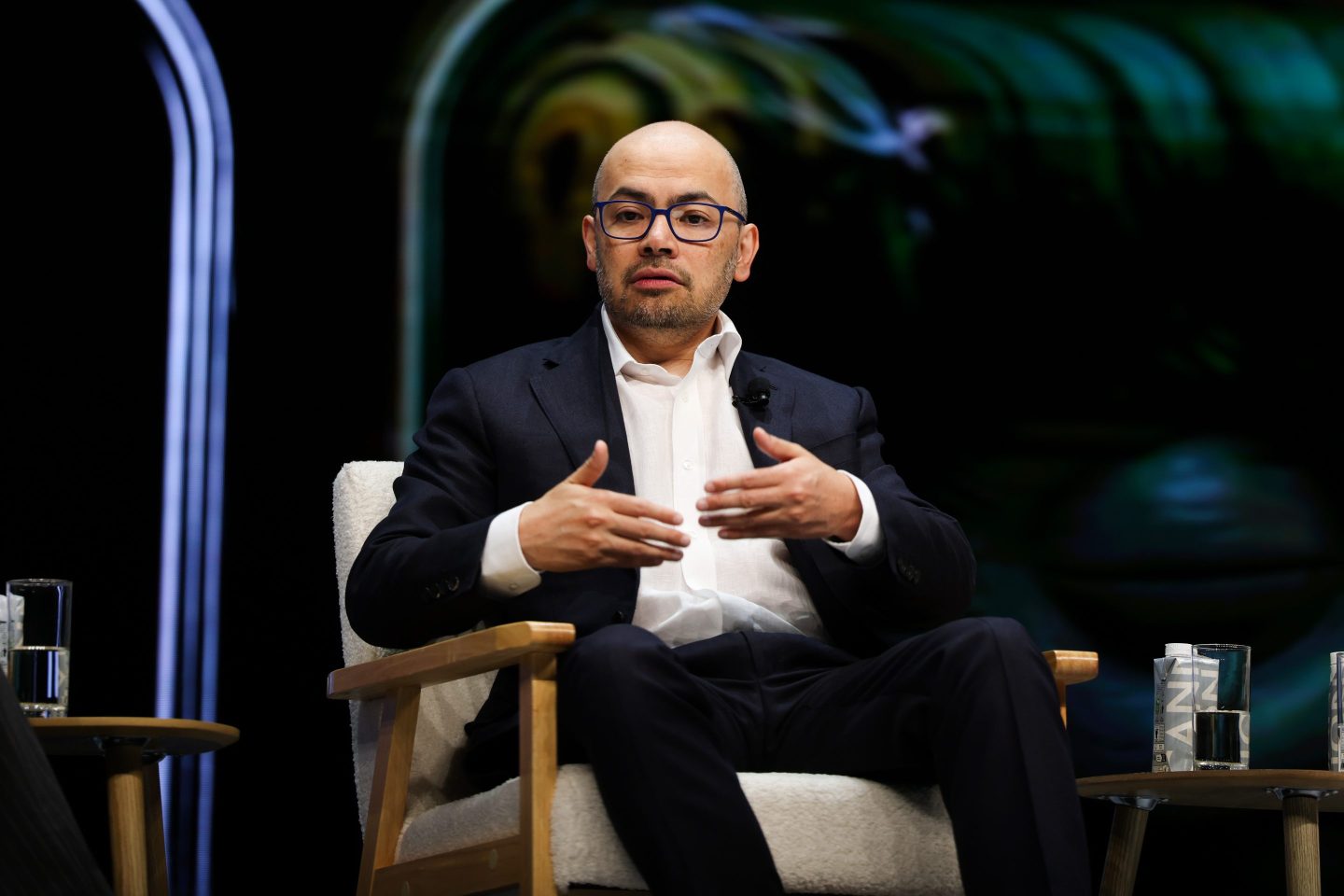 Demis Hassabis sitting in a chair.