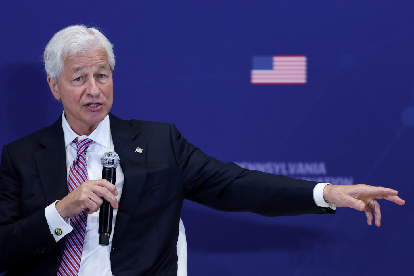 Photo of Jamie Dimon speaking with a blurred American flag behind him at a defense conference