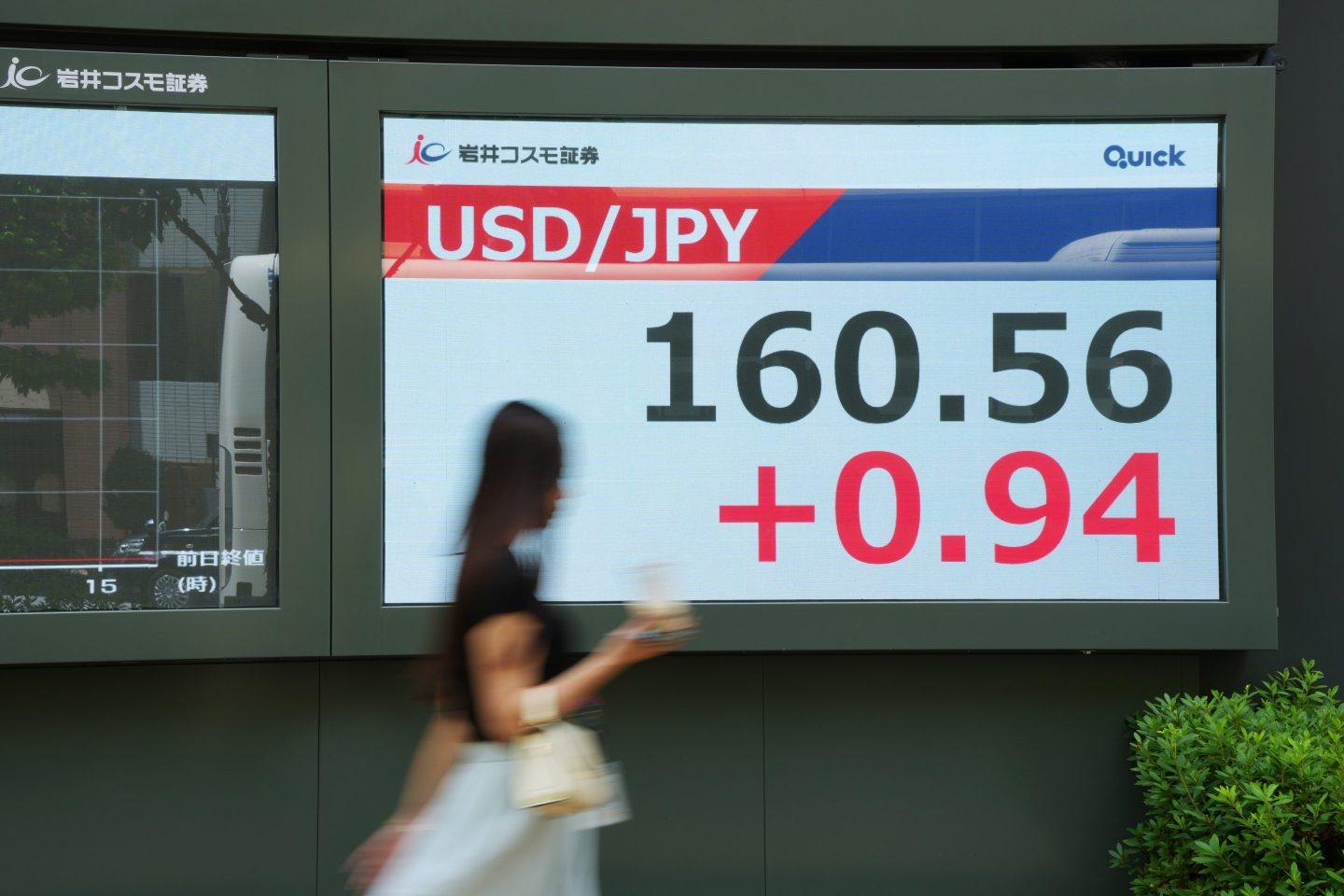 Photo of yen and dollar comparison and a woman walking past in a blur