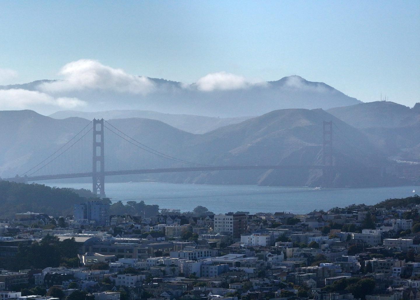 A view of Golden Gate Bridge and houses during warm weather in San Francisco, California, United States.