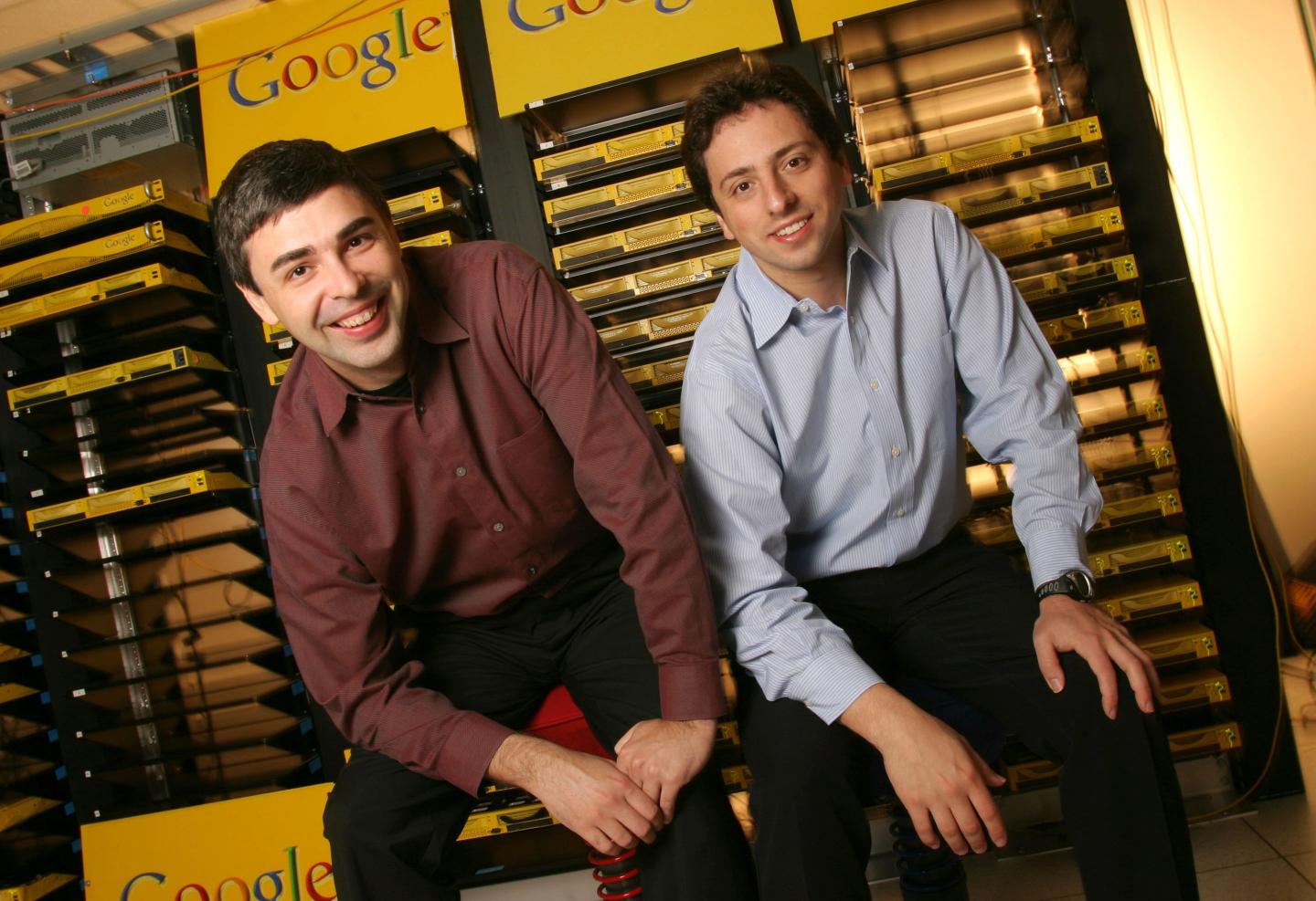 Larry Page and Sergey Brin smile in front of old Google servers.