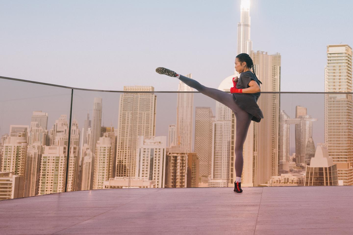 A woman on a rooftop practicing kickboxing.