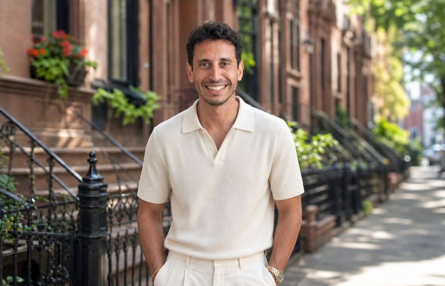 Noa Khamallah smiles in a white polo with his hands in his pockets