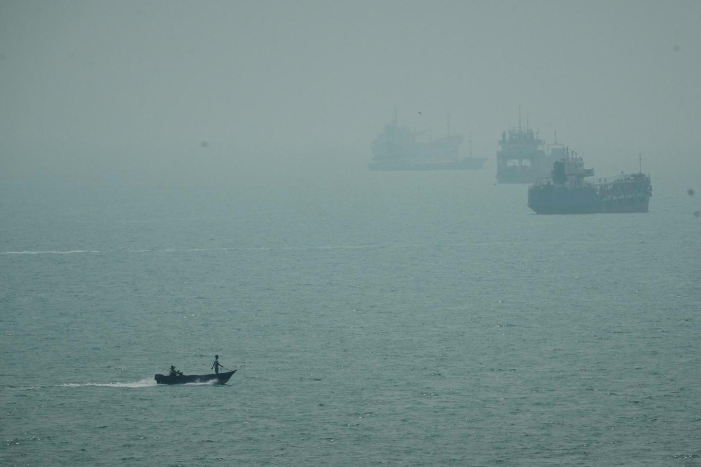 A motorboat travels past commercial vessels anchored amid haze in the Strait of Hormuz off Bandar Abbas, Iran, Monday, Sept. 7, 2026. 