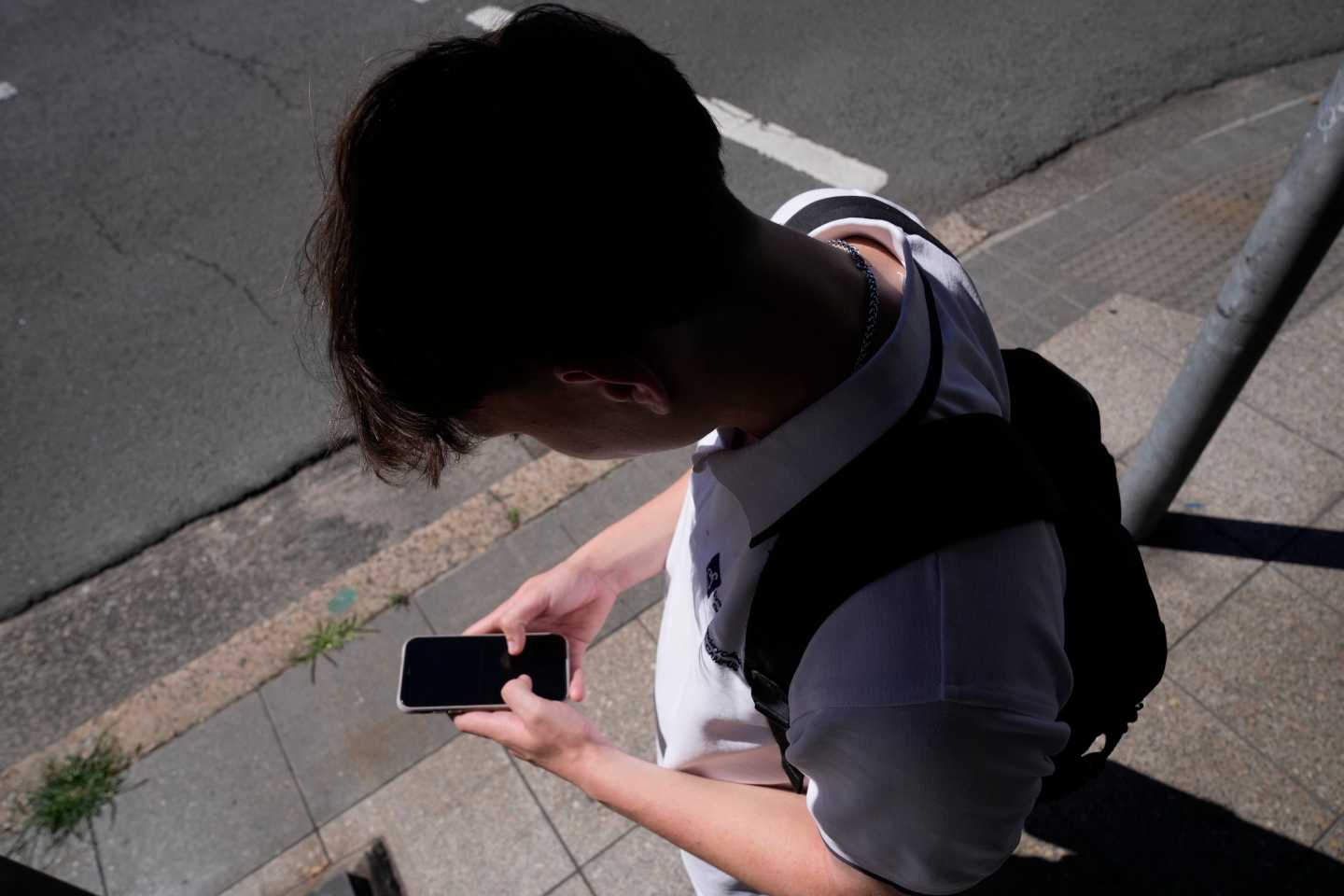 Photo of a kid staring at their phone with a shadow overhead