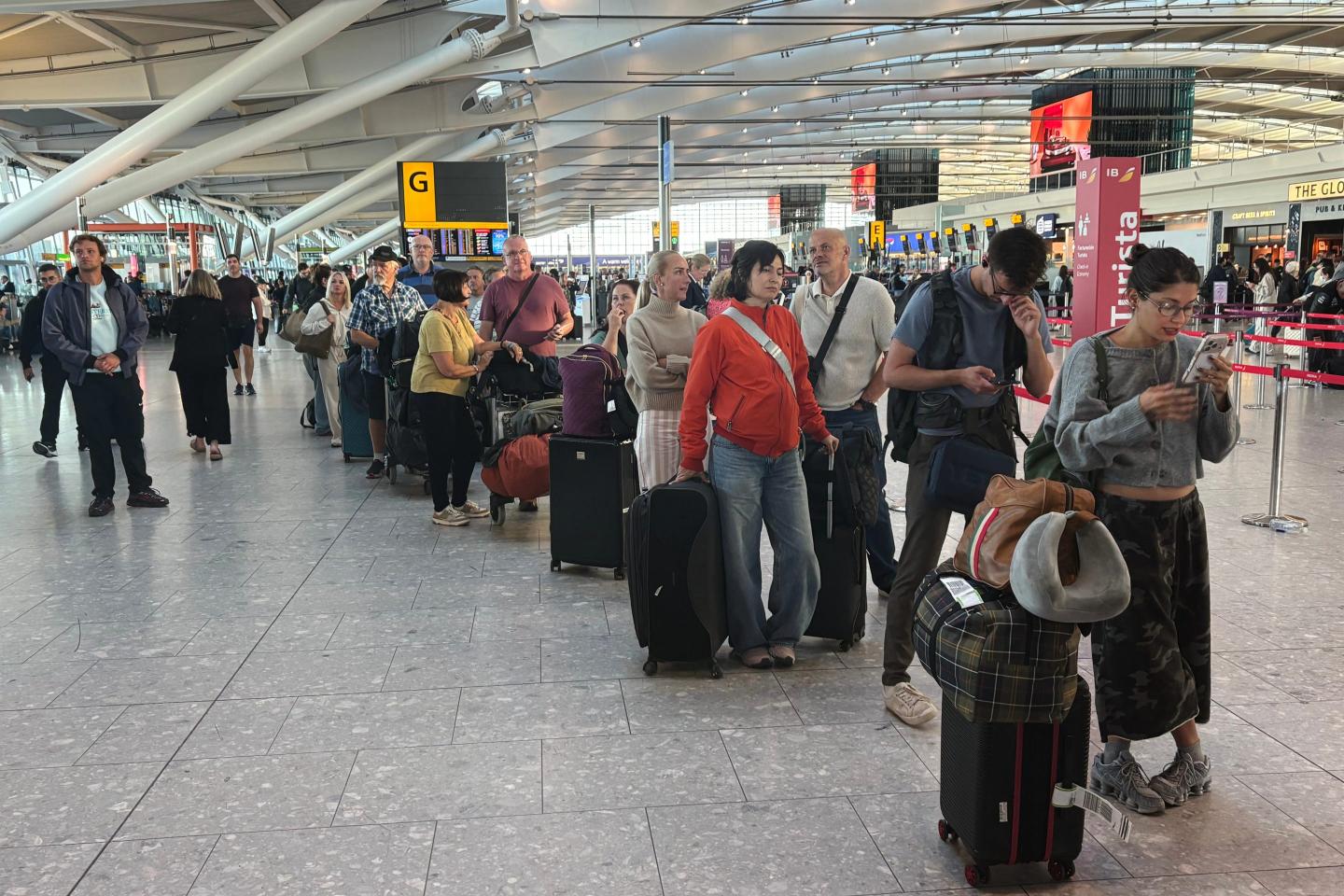 Passengers wait in line at Heathrow Airport in London, during an air traffic control problem that disrupted travel across Britain.