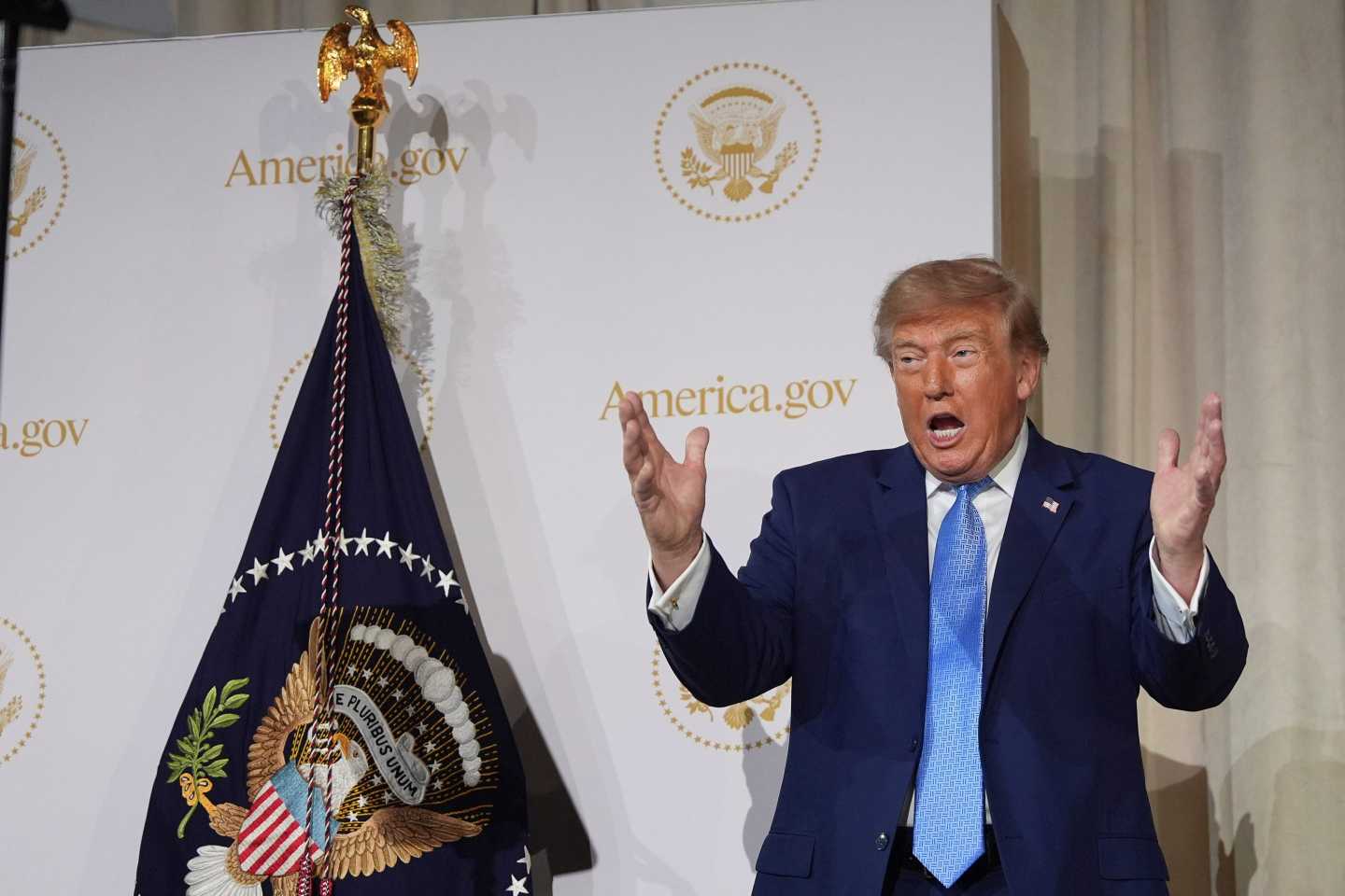 President Donald Trump gesturing as he speaks at the Andrew W. Mellon Auditorium.