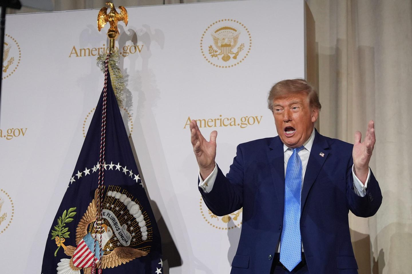 President Donald Trump gesturing as he speaks at the Andrew W. Mellon Auditorium.