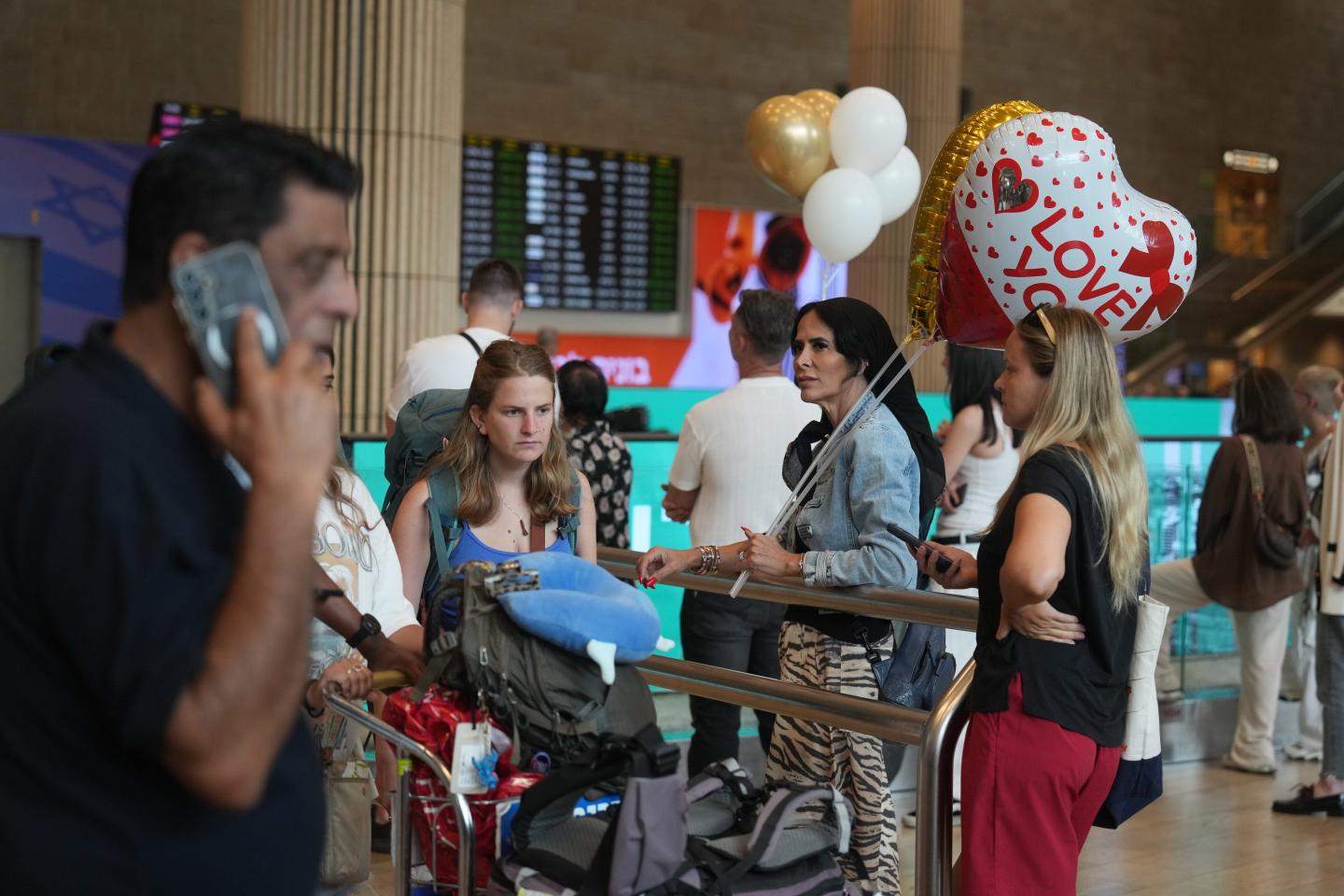 Holding balloons people wait for the arrival of passengers at Ben Gurion International Airport, near Tel Aviv, Israel