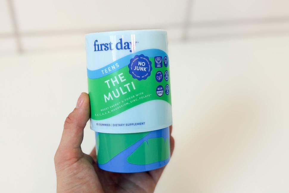Closeup of a hand holding a canister of First Day Teens' Multi gummies
