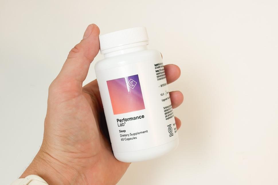 Closeup of a hand holding a bottle of Performance Lab Sleep capsules
