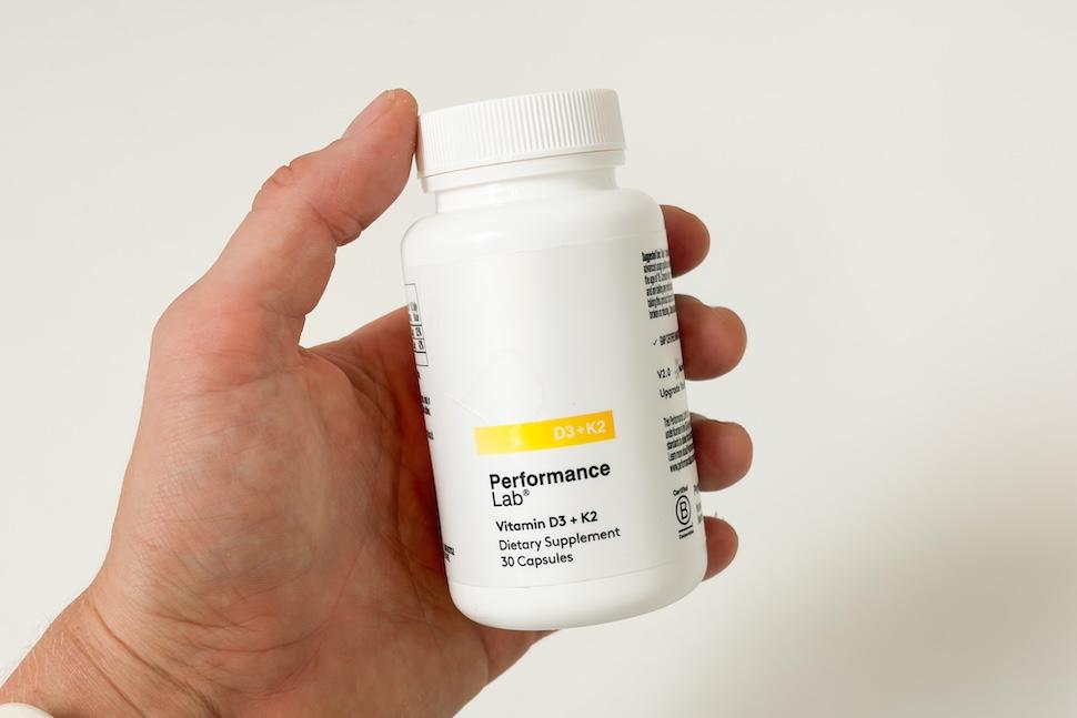 Closeup of a hand holding a bottle Performance Lab NutriGenesis D3 + K2