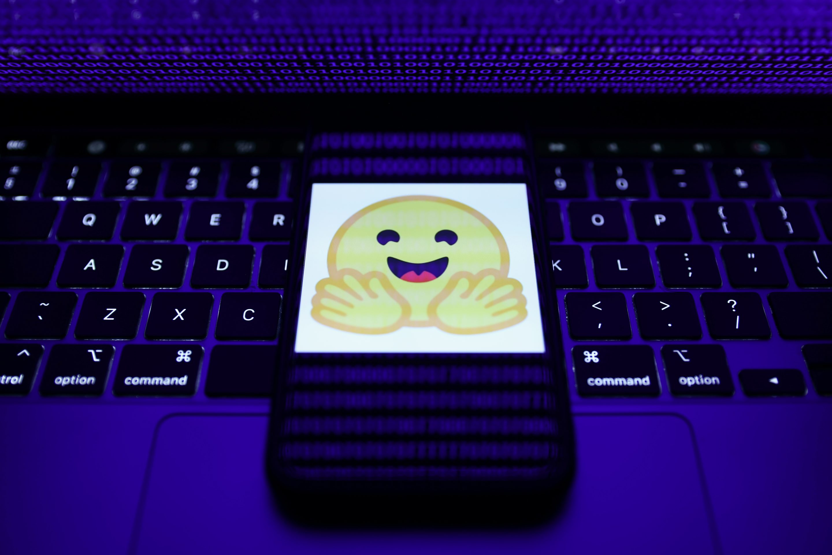 The Hugging Face logo on a smartphone resting on a laptop keyboard.
