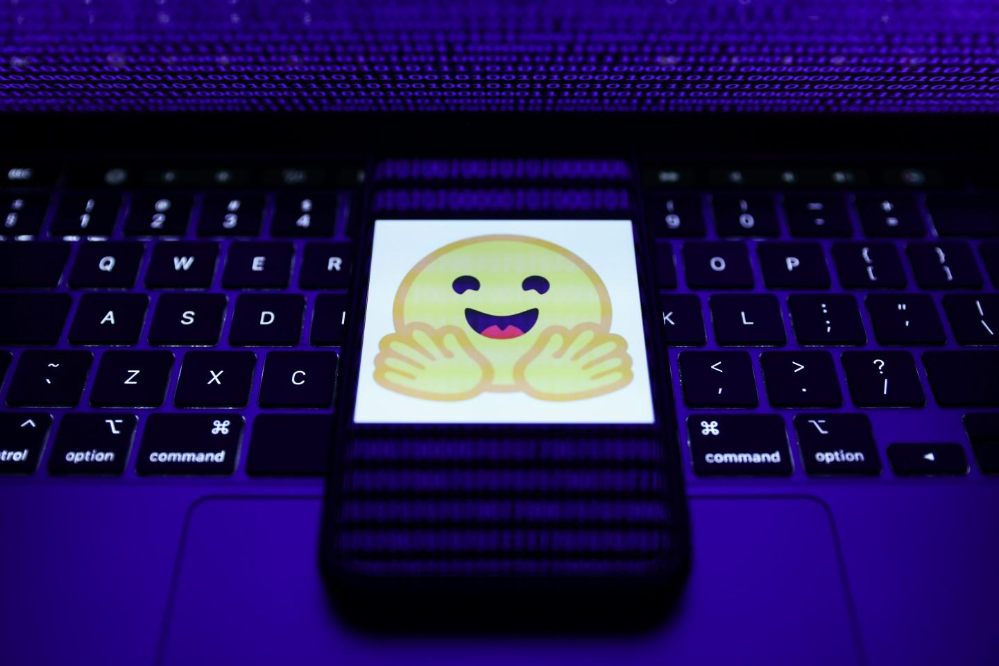 The Hugging Face logo on a smartphone resting on a laptop keyboard.