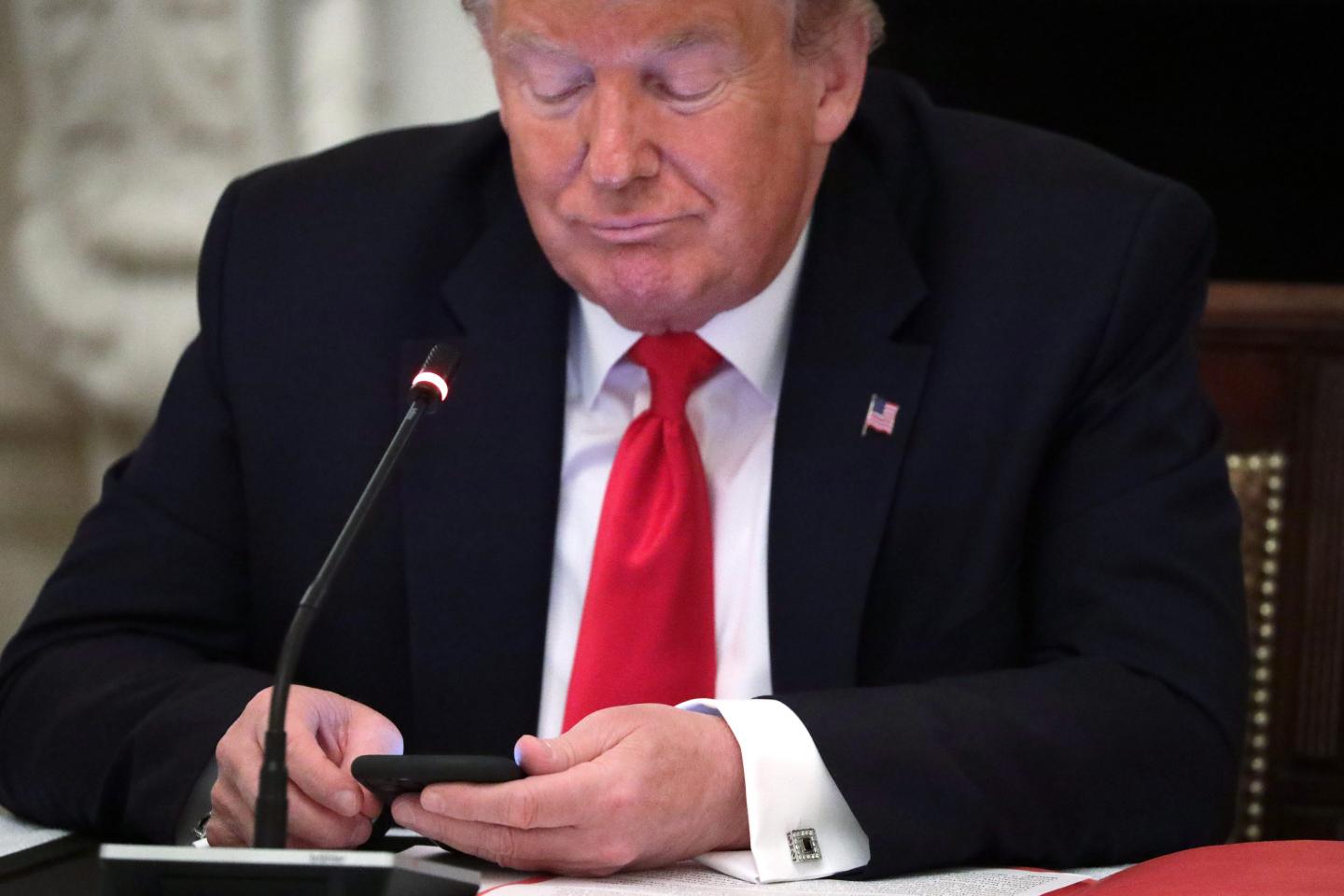 President Donald Trump looks at his phone during a roundtable at the State Dining Room of the White House June 18, 2020.