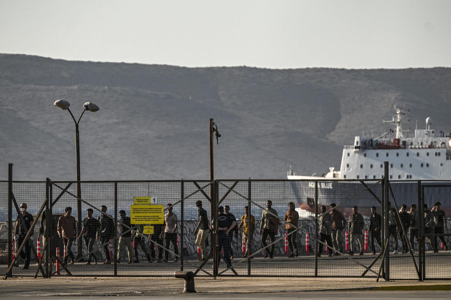 Migrants walk as they are gathered by Greek coast guard officers after disembarking from a cargo ship, in the port of Lavrio, south of Athens.