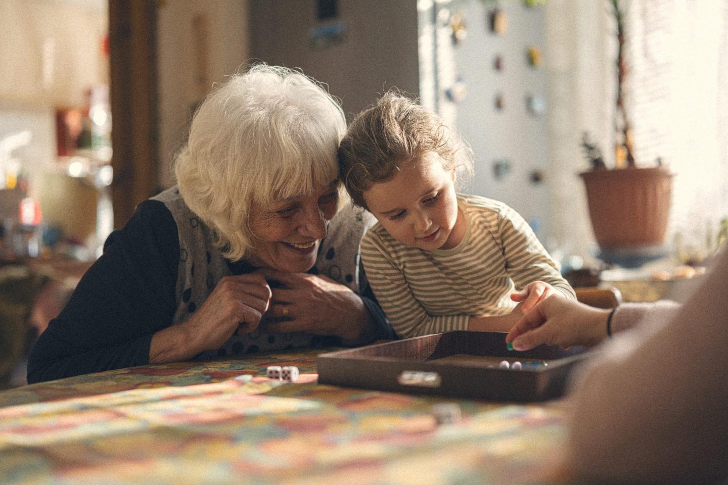 Multigenerational family get together, grandma, mom and child play chinese checkers in cozy home with warm light, creating loving atmosphere.