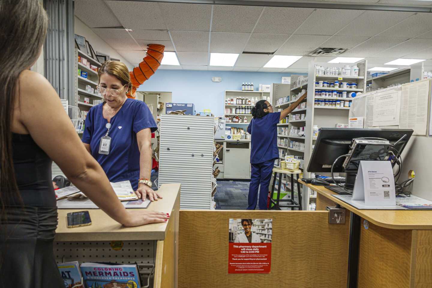 Miami Beach Florida, CVS Pharmacy, pharmacist talking to customer, technician organizing medicine shelves.