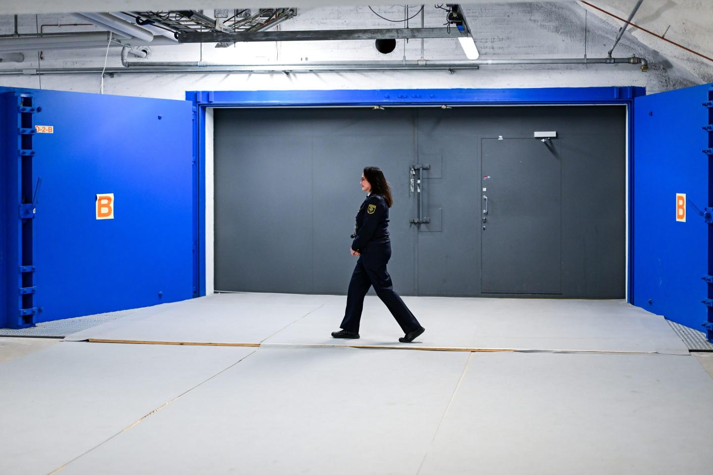 A woman from the City of Helsinki's Emergency Services and Fire Department walks past a bunker door during a visit by the foreign minister to the Merihaka civil defense facility.